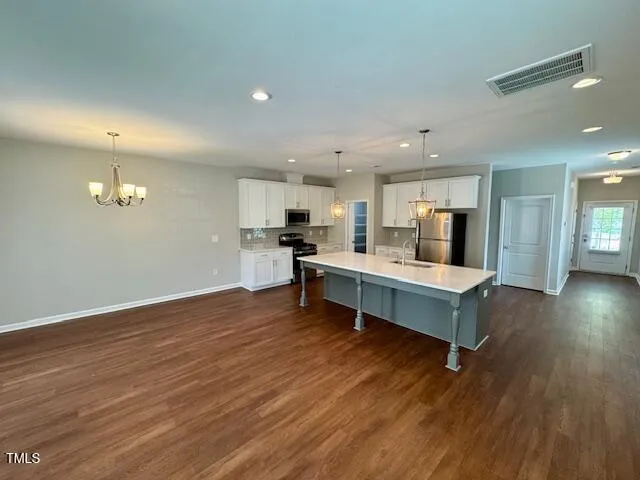 a kitchen with stainless steel appliances kitchen island wooden floors refrigerator and stove