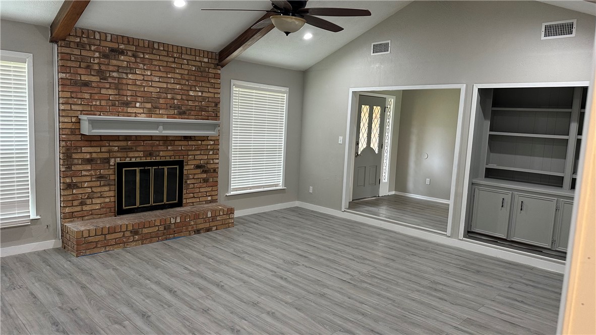 1010 Holt Street College Station, TX 77840 - Photo 2 of 14 an empty room with wooden floor fireplace and windows