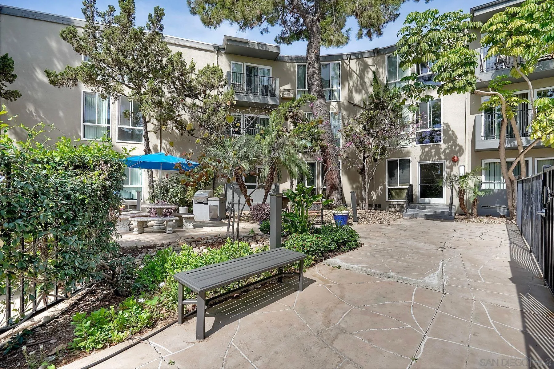 4860 Rolando Court, Unit 75 San Diego, CA 92115 - Photo 17 of 20 a view of a patio with table and chairs under an umbrella