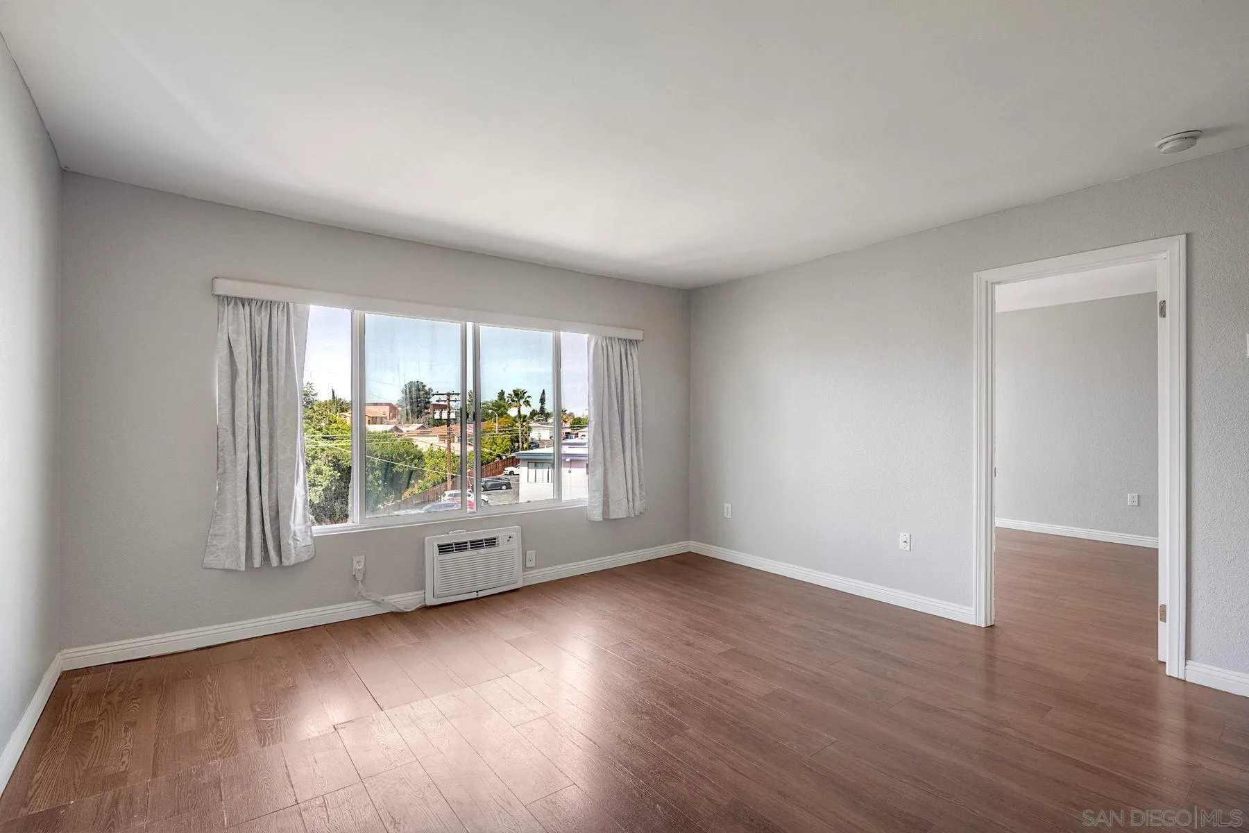 4860 Rolando Court, Unit 75 San Diego, CA 92115 - Photo 9 of 20 an empty room with wooden floor and windows