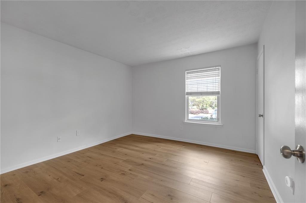 1150 Collier Road Northwest, Unit 2J Atlanta, GA 30318 - Photo 13 of 41 an empty room with wooden floor and windows