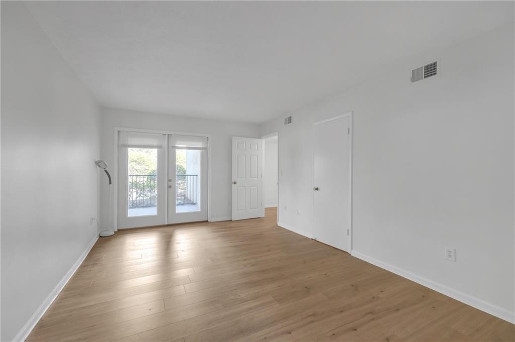 1150 Collier Road Northwest, Unit 2J Atlanta, GA 30318 - Photo 20 of 41 a view of an empty room with wooden floor and a window
