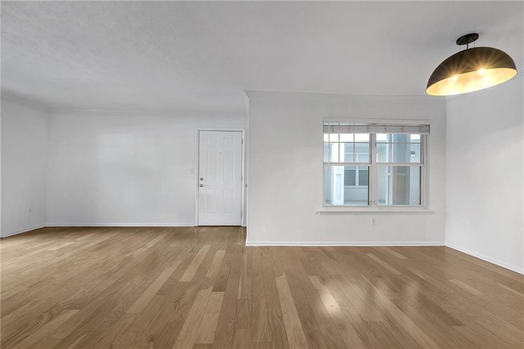 1150 Collier Road Northwest, Unit 2J Atlanta, GA 30318 - Photo 2 of 41 a view of an empty room with window and wooden floor