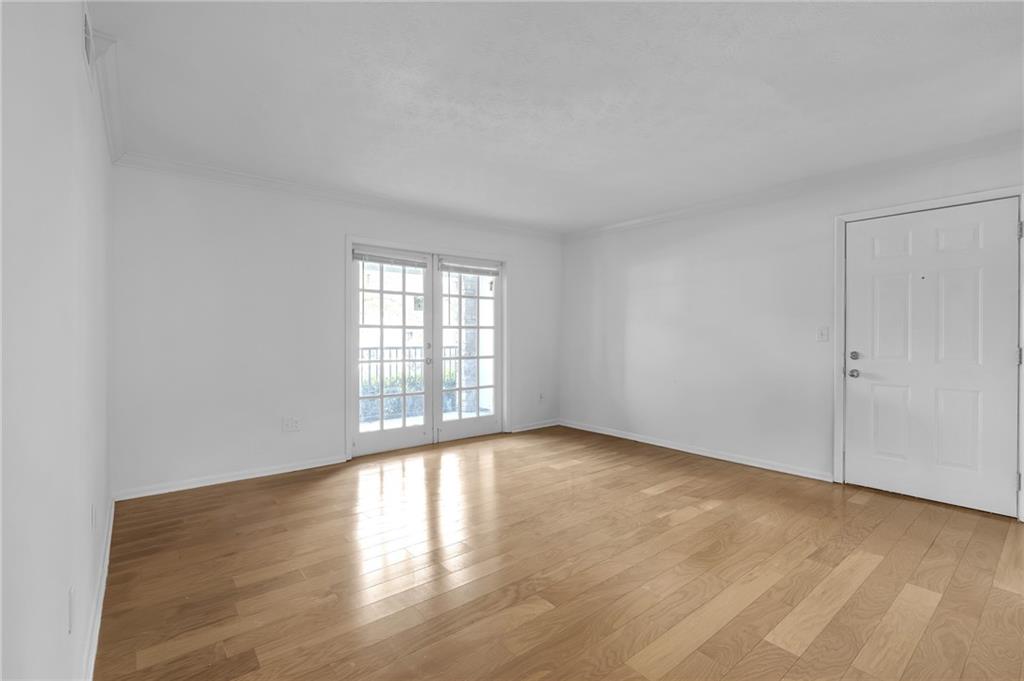 1150 Collier Road Northwest, Unit 2J Atlanta, GA 30318 - Photo 8 of 41 a view of an empty room with wooden floor and a window