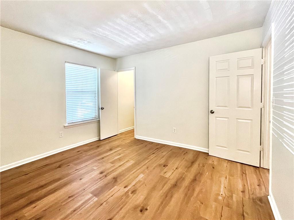 1150 Collier Road Northwest, Unit 2J Atlanta, GA 30318 - Photo 10 of 33 an empty room with wooden floor and windows
