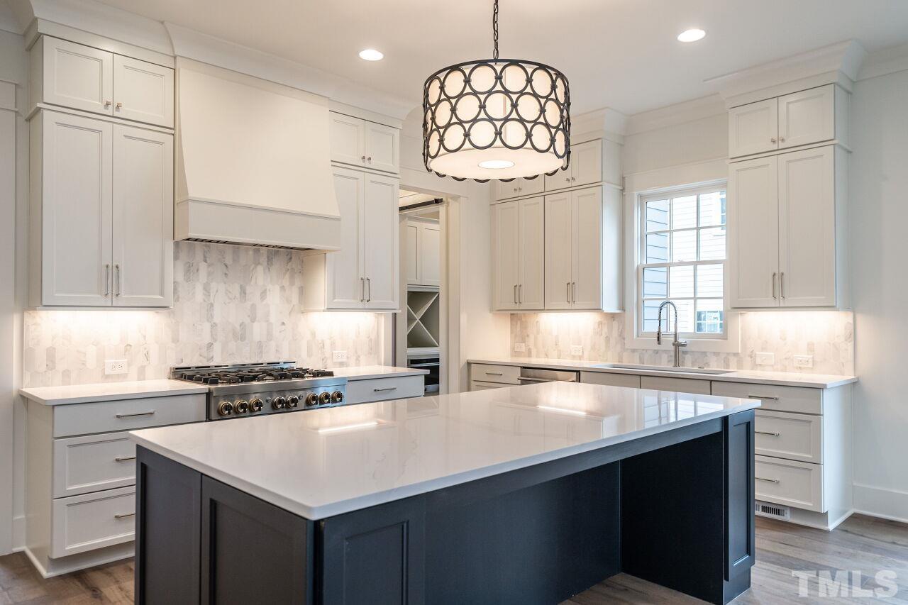 1104 Shelley Road Raleigh, NC 27609 - Photo 14 of 45 a kitchen with a sink a center island cabinets and stainless steel appliances