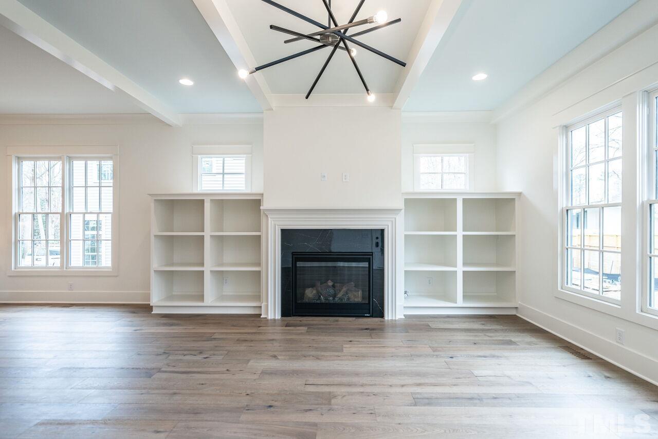 1104 Shelley Road Raleigh, NC 27609 - Photo 24 of 45 an empty room with a fireplace and wooden floor