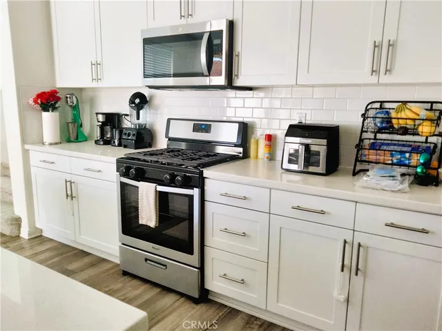 a kitchen with cabinets stainless steel appliances and a wooden floor