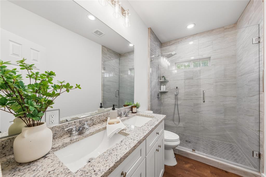 1128 Newton Road Ferris, TX 75125 - Photo 14 of 28 Bathroom featuring a dual vanity with a granite countertop, white cabinetry, and undermount sinks