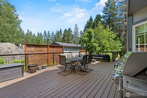 a view of a roof deck with table and chairs a barbeque with wooden floor and fence