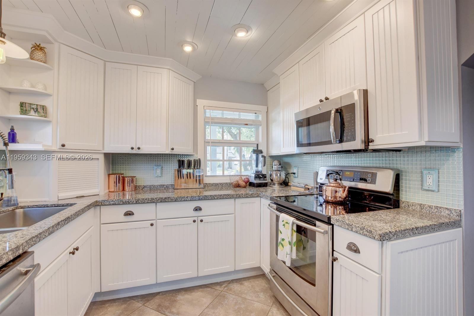 1210 Southwest 19th Street Boca Raton, FL 33486 - Photo 16 of 43 a kitchen with granite countertop white cabinets and white appliances