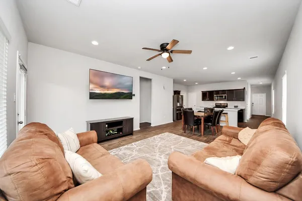 a living room with furniture and a flat screen tv with kitchen view