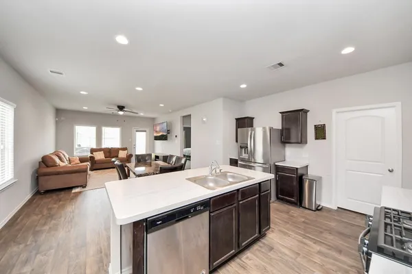 a large kitchen with stainless steel appliances a stove a sink dishwasher and a refrigerator with wooden floor