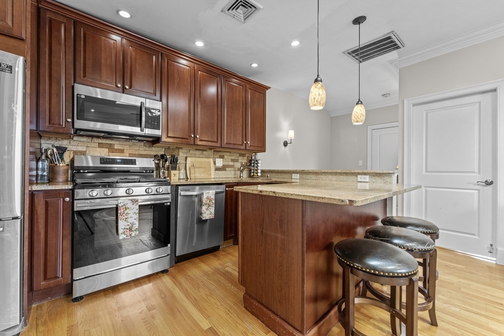 10 Mitchell Street, Unit 3 Boston, MA 02127 - Photo 5 of 15 a kitchen with kitchen island granite countertop wooden cabinets stainless steel appliances and a counter top space