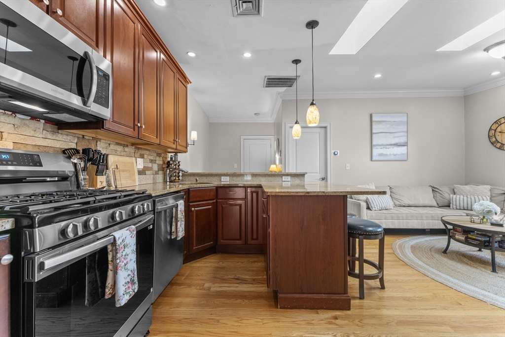 10 Mitchell Street, Unit 3 Boston, MA 02127 - Photo 6 of 15 a kitchen with stainless steel appliances granite countertop a stove a sink dishwasher and a microwave oven with white cabinets