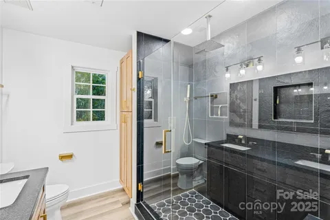 a bathroom with a granite countertop sink a toilet a mirror and shower