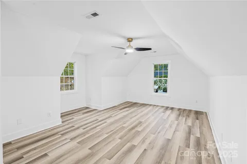 an empty room with windows and ceiling fan