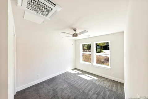an empty room with a window and ceiling fan