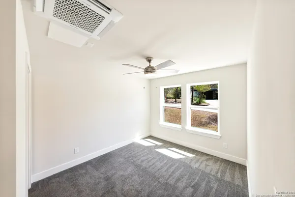 an empty room with a window and ceiling fan