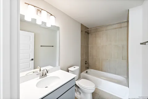 a bathroom with a sink a toilet a mirror a bathtub and shower