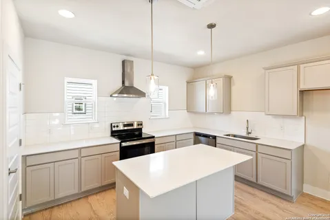 a kitchen with a sink stove oven and white cabinets
