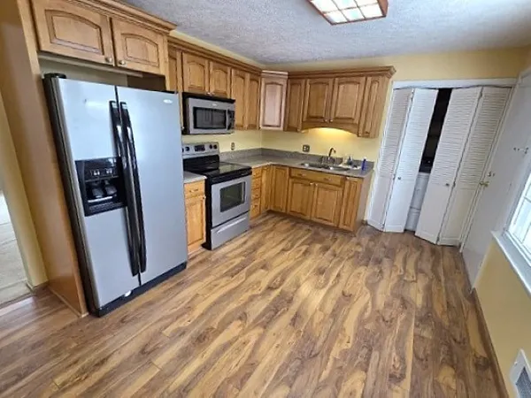 a kitchen with granite countertop a refrigerator stove and wooden floor