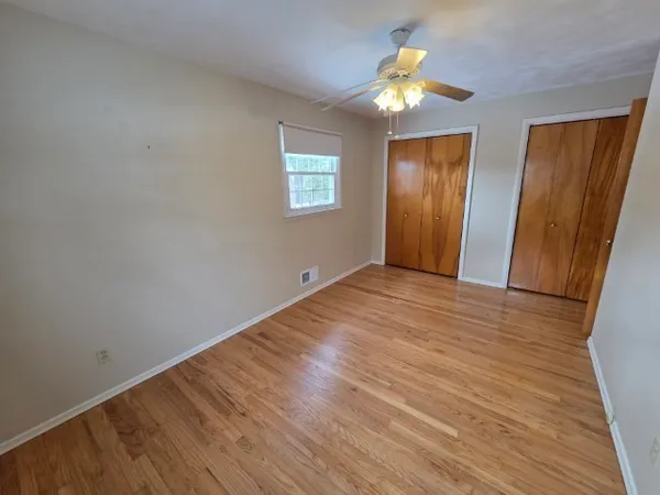 a view of empty room with wooden floor and fan