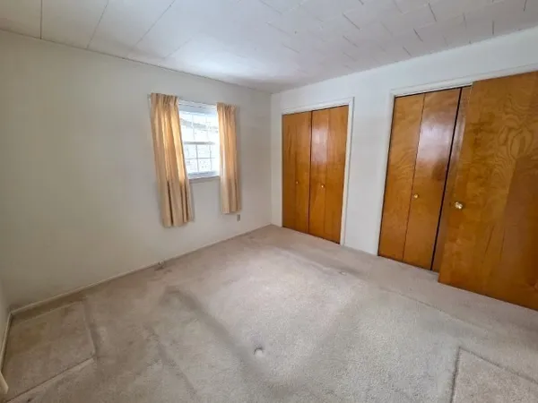 a view of an empty room with windows and closet