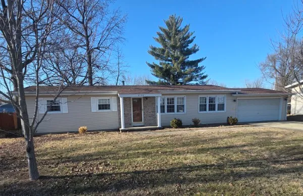 a front view of a house with a yard covered with trees