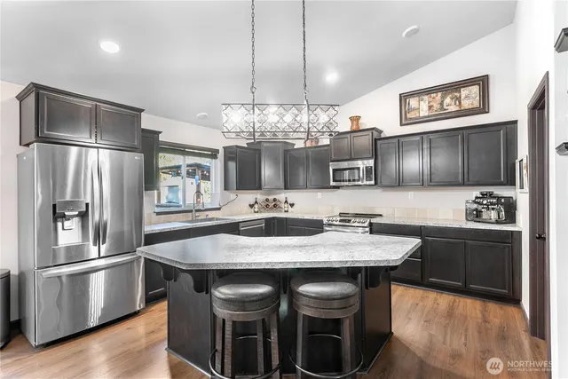 a kitchen with granite countertop a refrigerator and a stove top oven