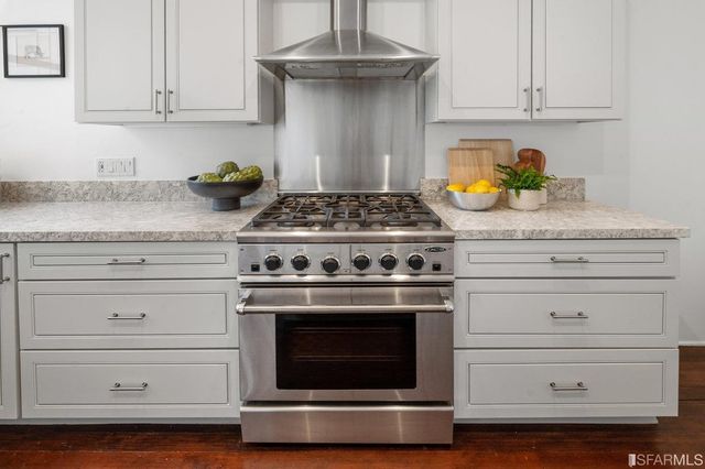 a stove top oven sitting inside of a kitchen and white cabinets