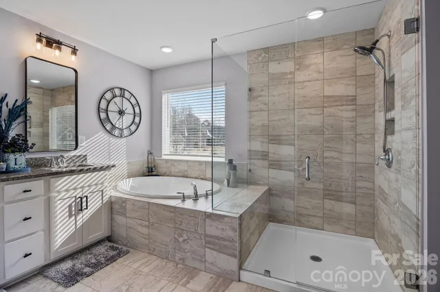 a bathroom with a bathtub a sink a mirror a vanity and a shower
