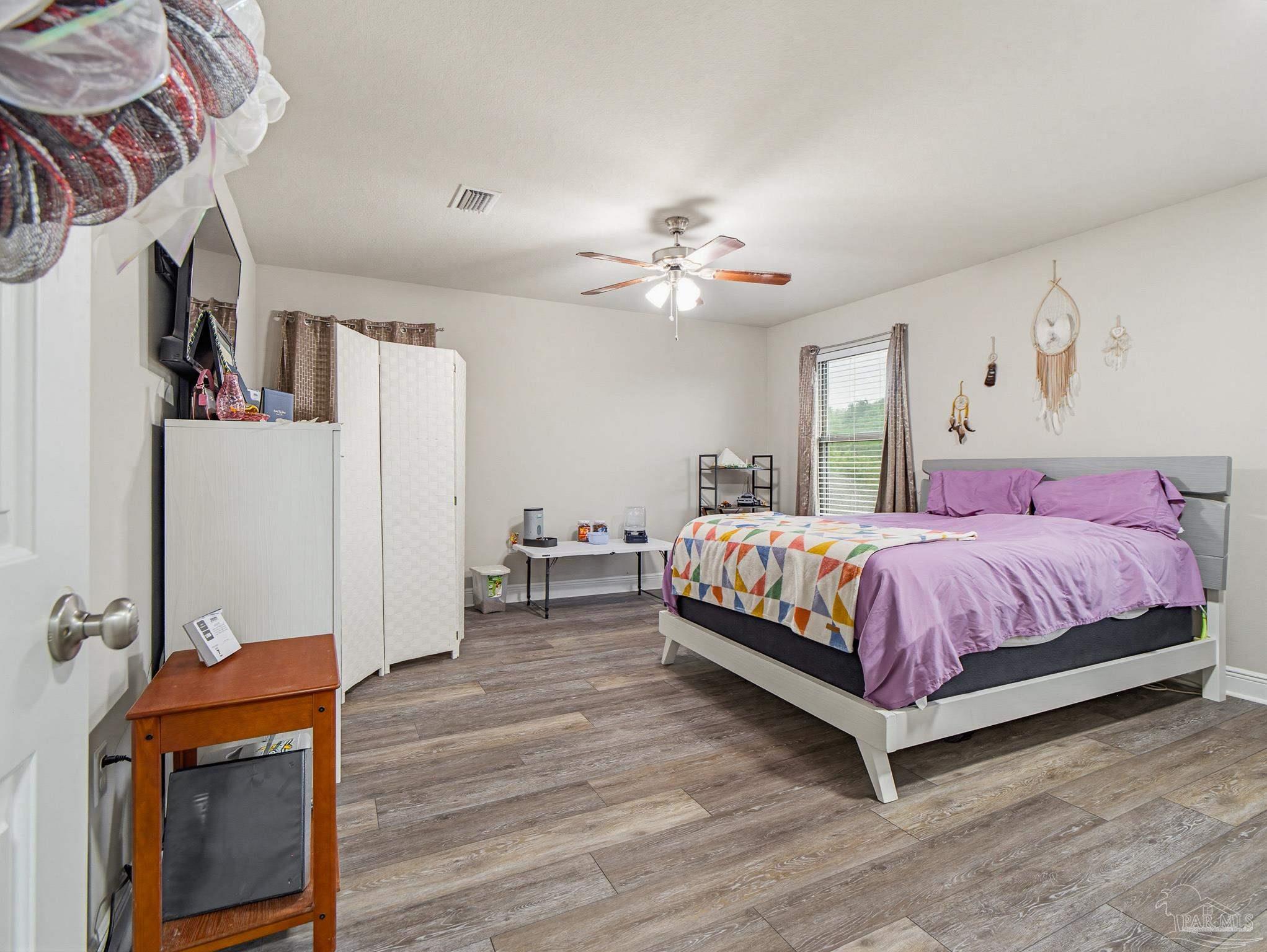 6294 Ladera Trail Pace, FL 32571 - Photo 45 of 50 a spacious bedroom with a bed and a chandelier