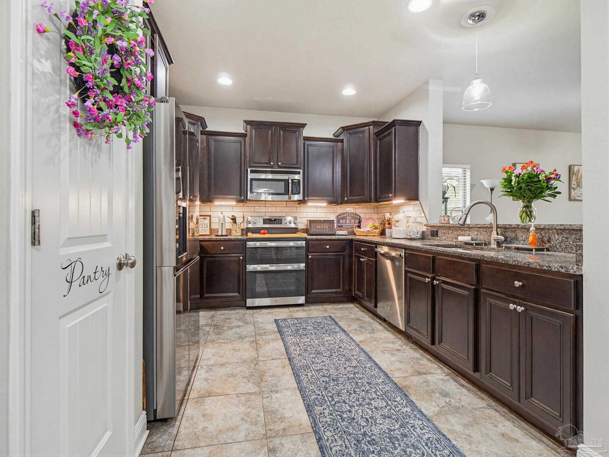 6294 Ladera Trail Pace, FL 32571 - Photo 10 of 50 a kitchen with stainless steel appliances granite countertop a sink and a refrigerator