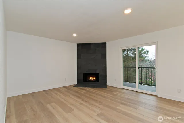 an empty room with wooden floor fireplace and windows