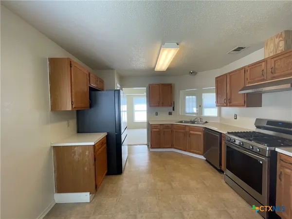 a large kitchen with stainless steel appliances granite countertop a stove a sink and a refrigerator