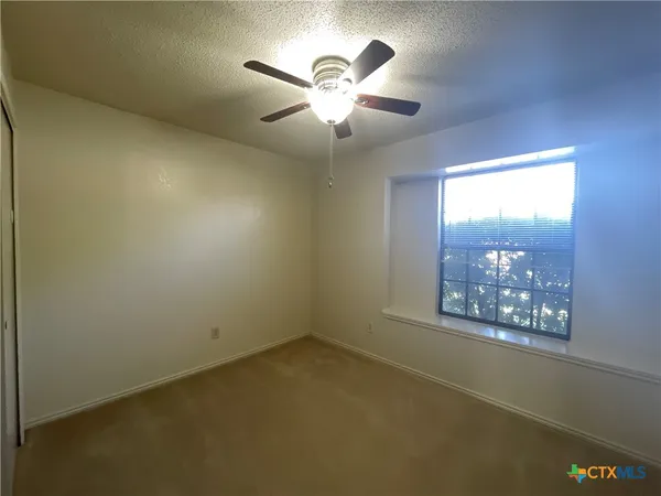 an empty room with windows and fan