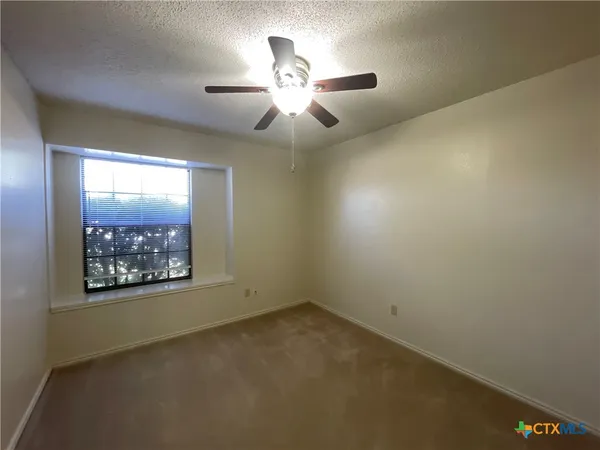 an empty room with a ceiling fan and window