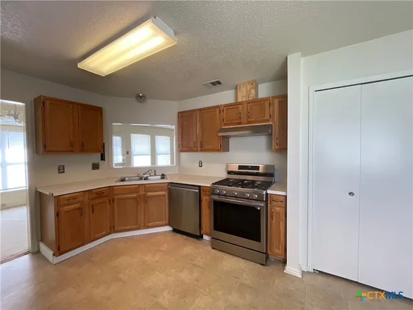 a kitchen with stainless steel appliances granite countertop a stove a sink and a refrigerator