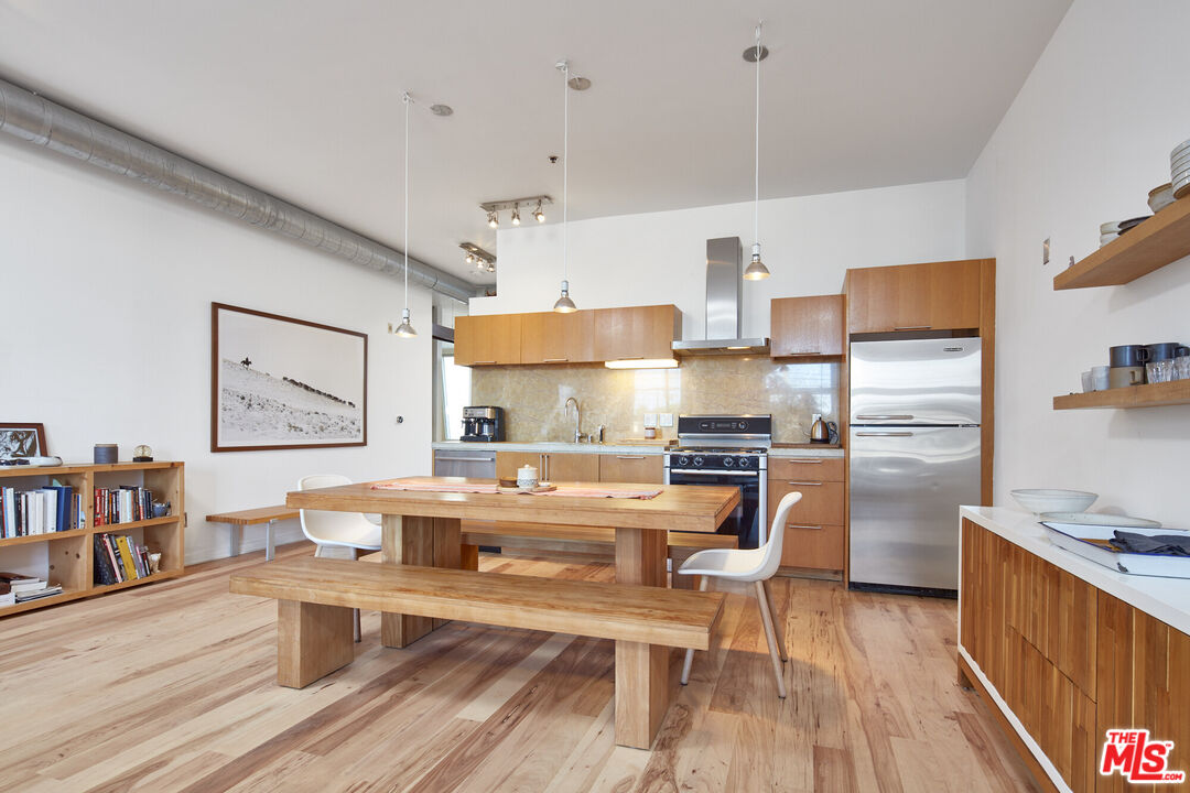 a kitchen with stainless steel appliances a stove a refrigerator and wooden floors