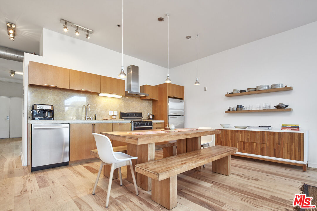 615 Hampton Drive, Unit B201 Venice, CA 90291 - Photo 4 of 39 a kitchen with stainless steel appliances kitchen island granite countertop a table chairs in it and wooden floors