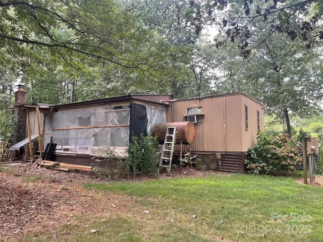 a backyard of a house with wooden fence and a large tree