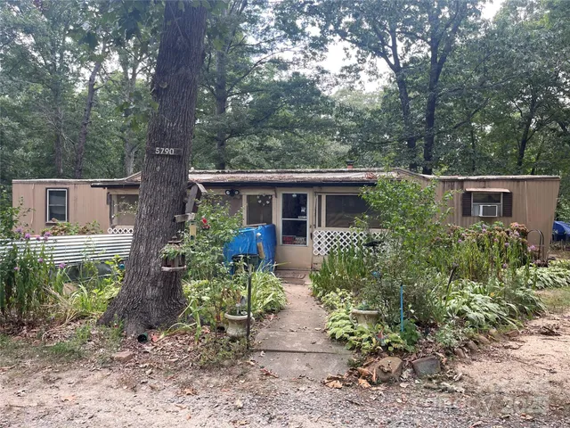 a view of house with a yard and potted plants