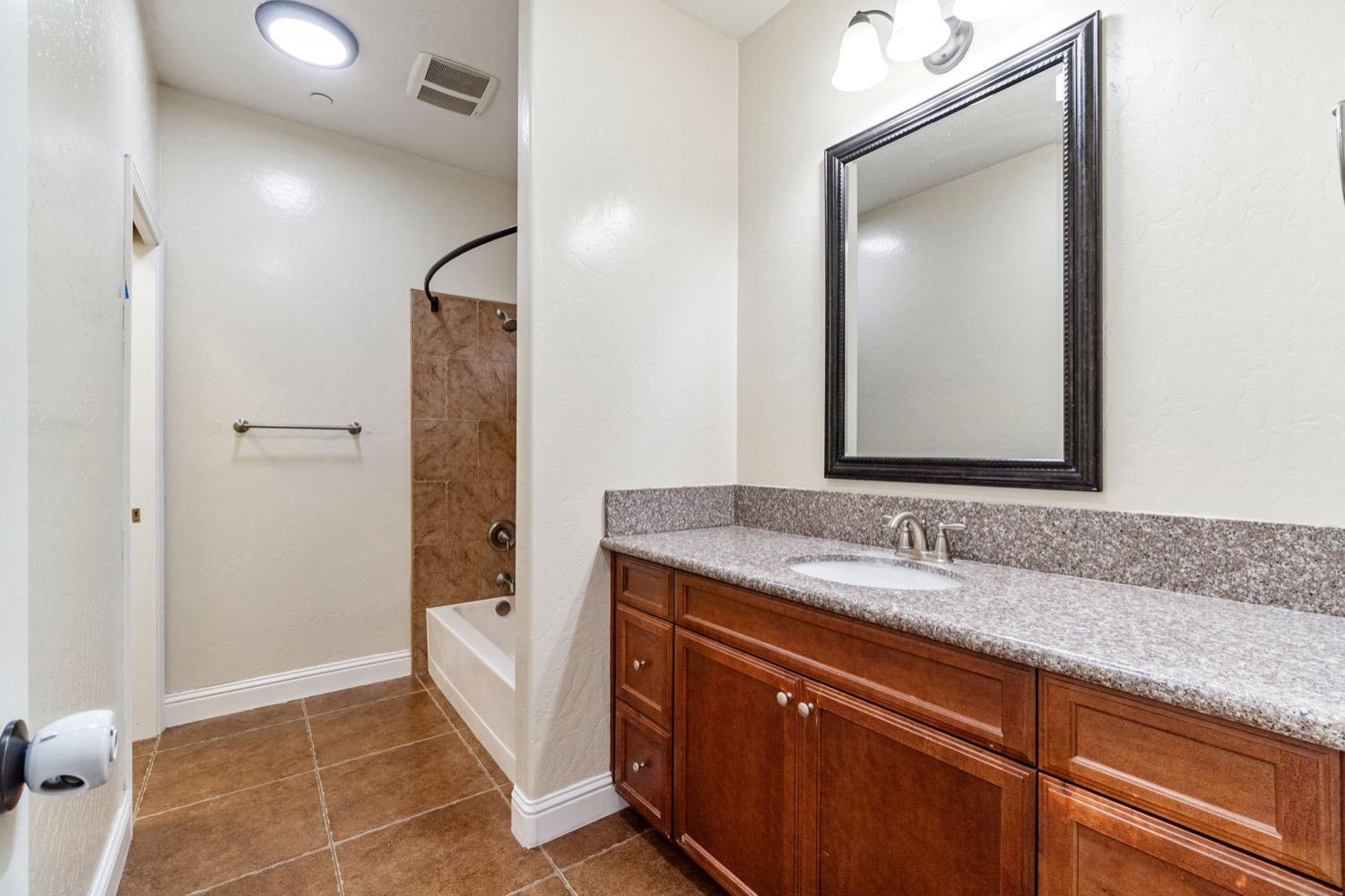 1156 Berry Drive Madera, CA 93637 - Photo 21 of 29 a bathroom with a granite countertop sink mirror and shower