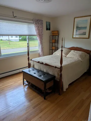 a bedroom with a bed window and wooden floor