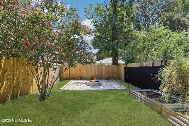a view of an empty room with wooden floor fireplace and a window