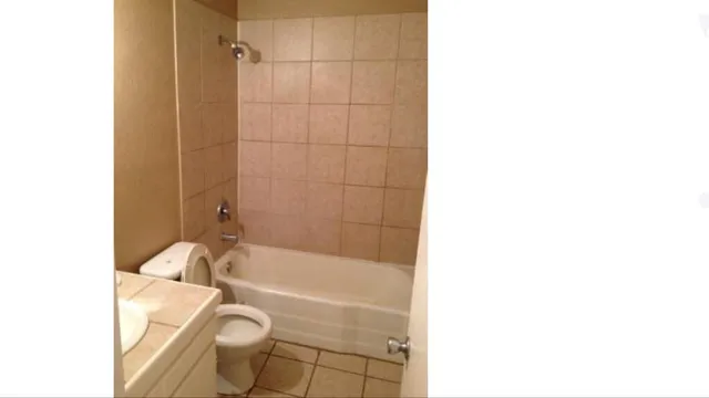 a bathroom with a granite countertop bathtub shower sink vanity and a toilet