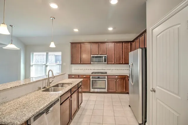 a kitchen with stainless steel appliances granite countertop a sink stove and refrigerator