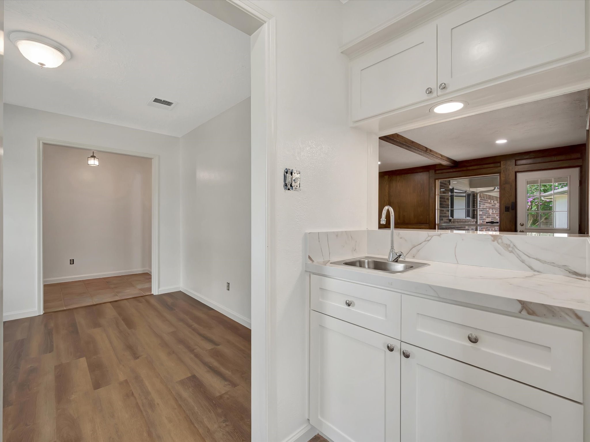 10340 Rocky Hollow Road La Porte, TX 77571 - Photo 7 of 38 Stunning wet bar featuring elegant quartz countertops and custom wood cabinetry, seamlessly flowing into the kitchen and living area.