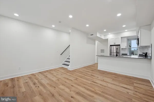 a view of kitchen with stainless steel appliances a refrigerator and wooden floor